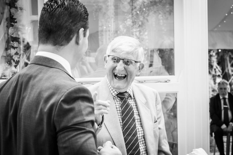 an older wedding guest and his son share a joke photographed in yorkshire