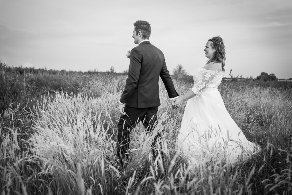a bride and groom walk leisurely through a field in east yorkshire