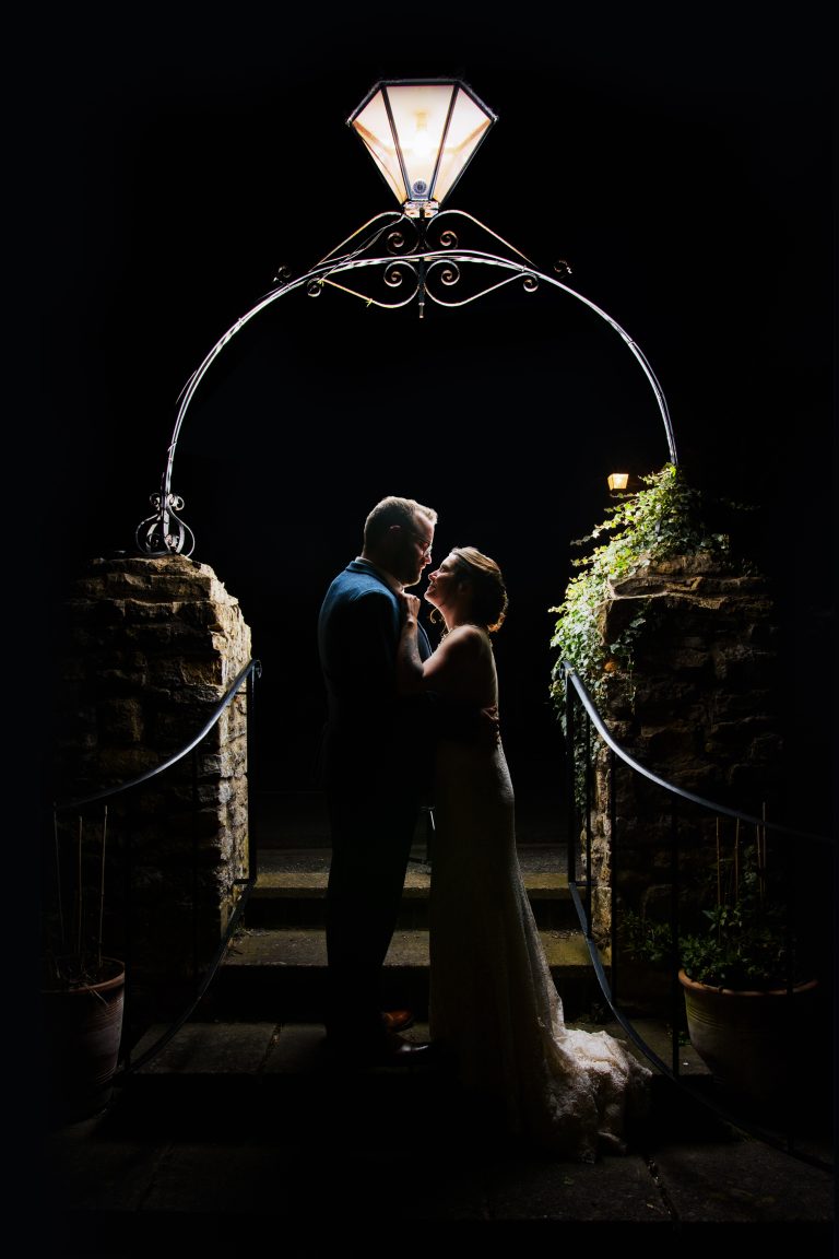 wedding photographer captures a newly married couple kissing beneath a lantern