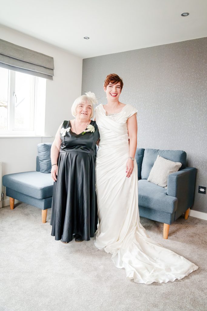 a bride in a wedding dress with medium length train and her mother scaled