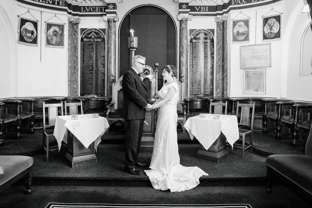 bride and groom holding hands in ceremony room in minerva masonic lodge hull scaled